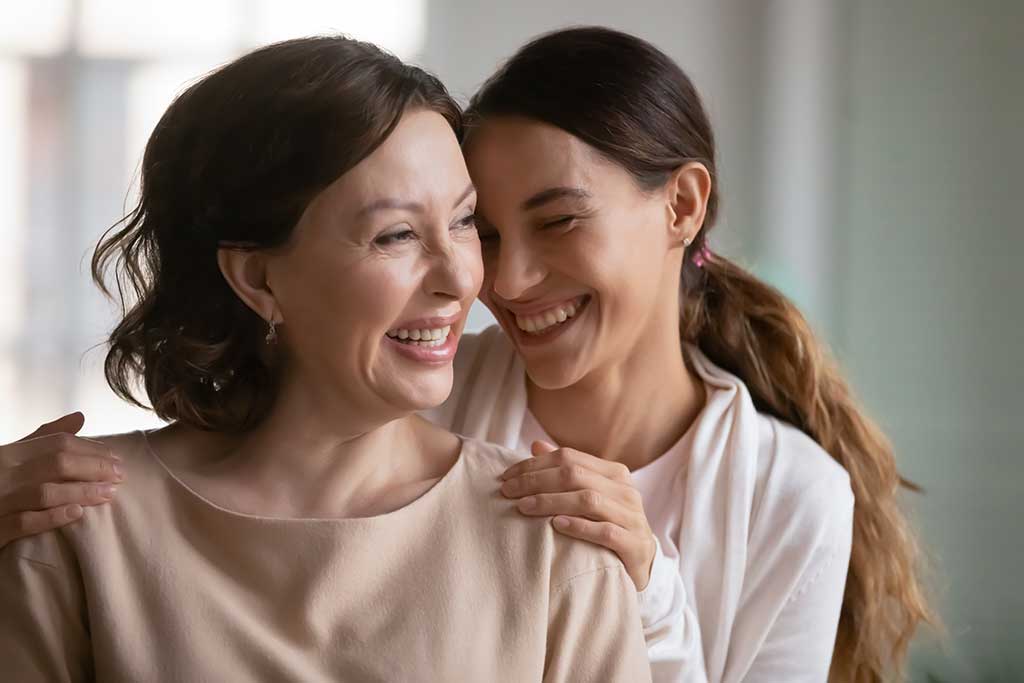 Close up overjoyed middle aged mother and grownup daughter cuddling